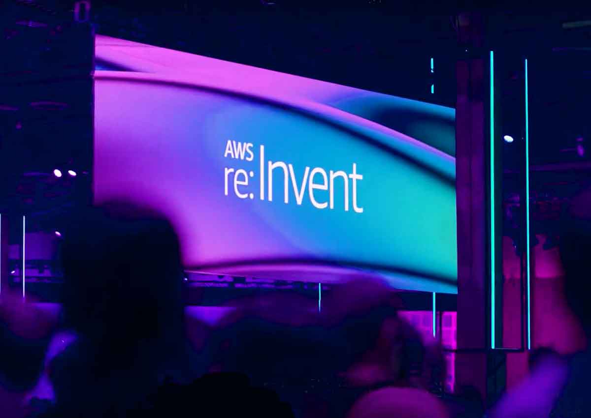 A photograph from the auditorium of the re:Invent stage. A backdrop shows the re:Invent 2019 logo