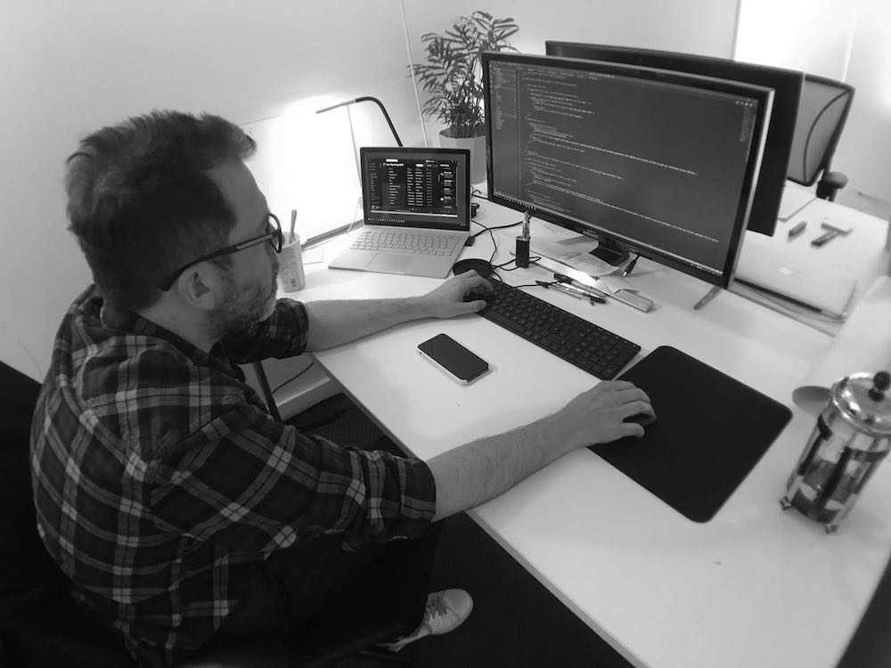 Martin Hicks, sat working at his computer. Photo taken from behind.